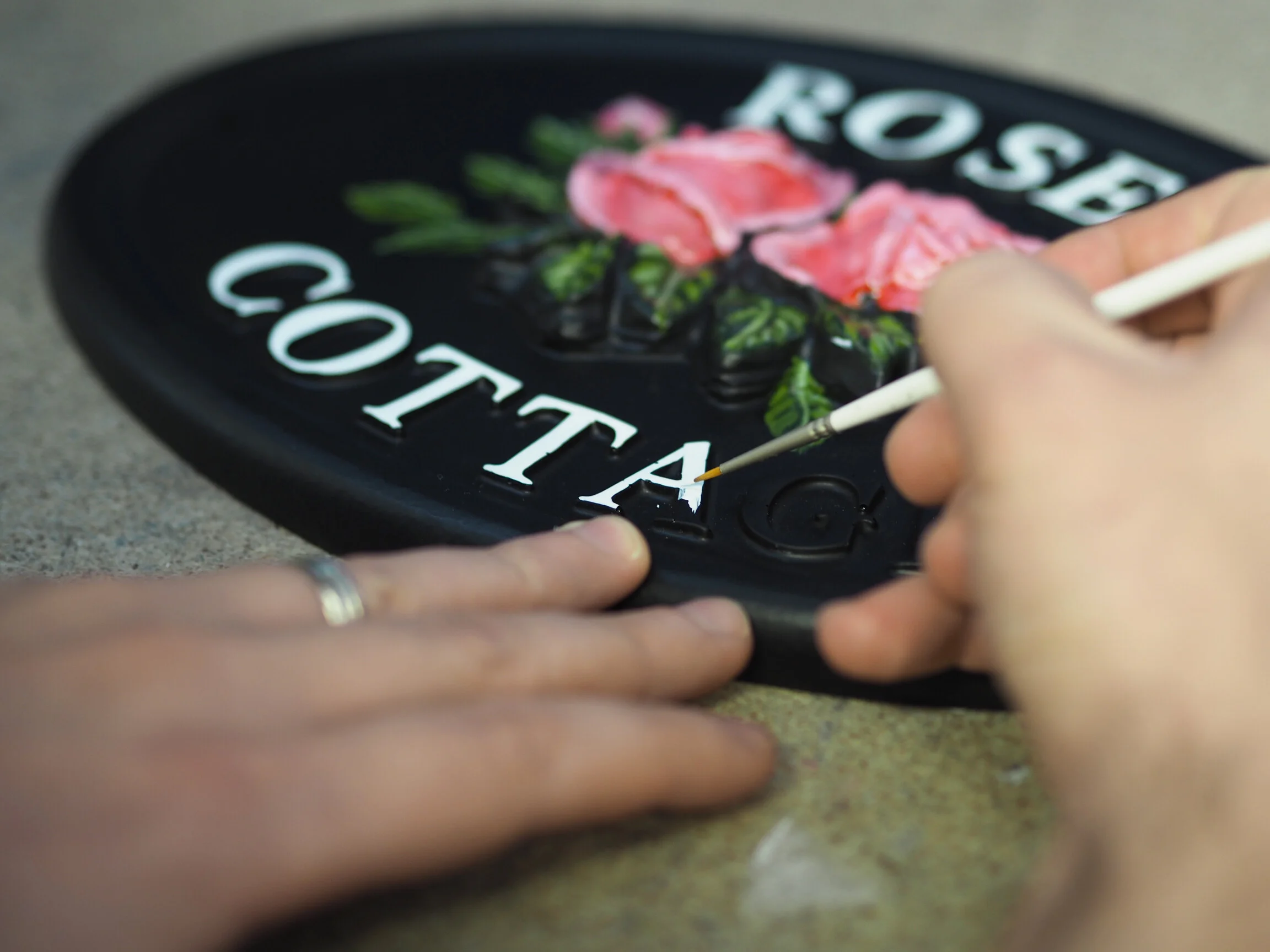 Close-up of hand painting on resin sign