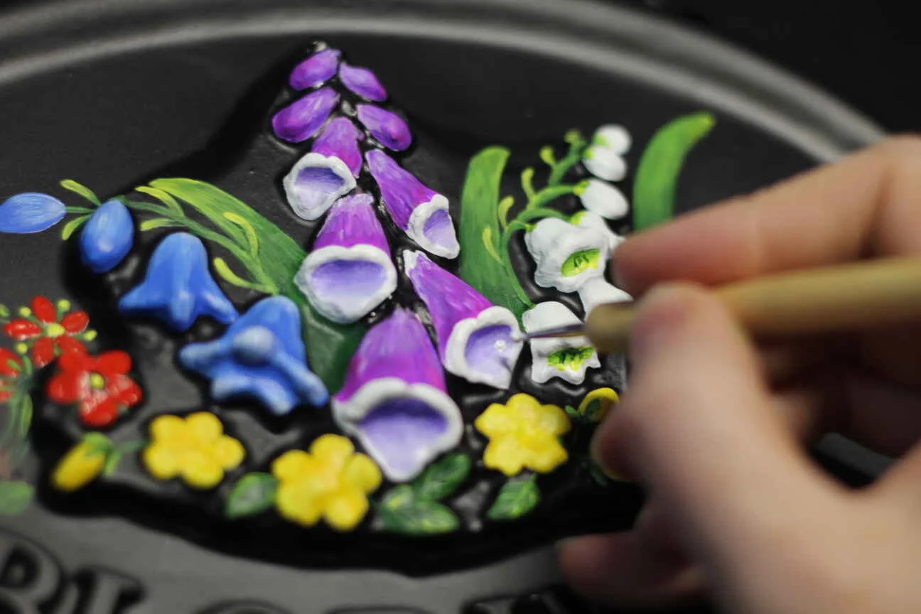 A close up of a house sign being painted with wildflowers